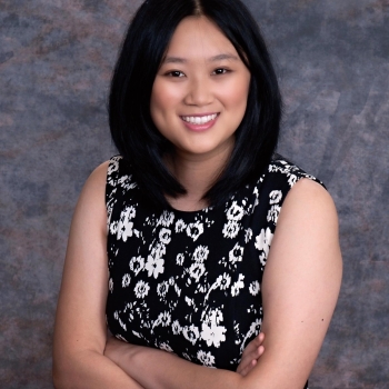 NHC member Amanda Meng is wearing a black and white flowered top, smiling and arms folded.