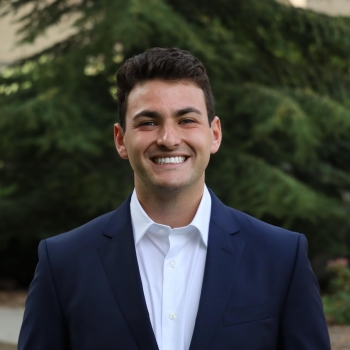 NHC member Brendan Reitman wearing a suit and smiling.
